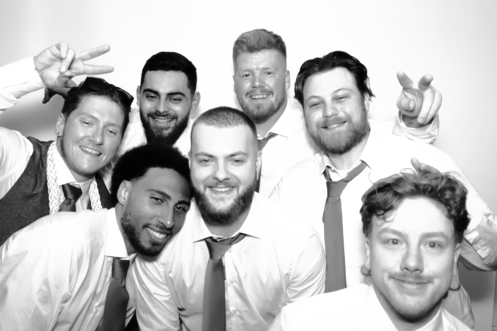 Seven guests packed into the booth, arms up